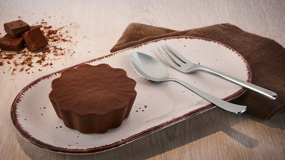 Warmer Schokoladenkuchen in Blütenform auf einem Teller, daneben Löffel und Kuchengabel