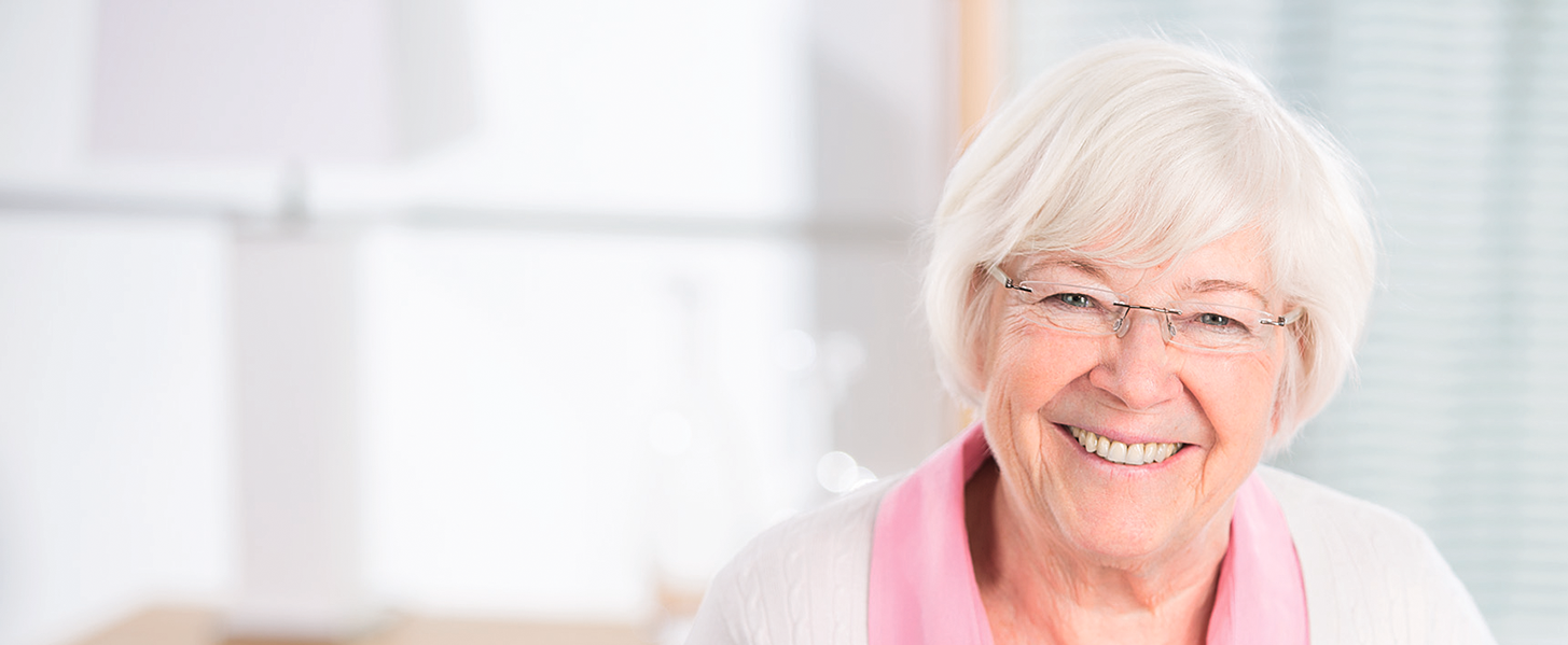 Porträt einer lächelnden älteren Frau mit Brille und weißem Haar