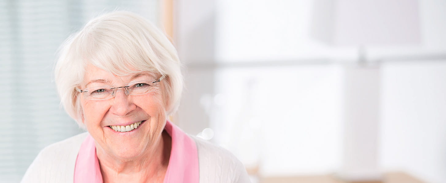 Eine Seniorin schaut freundlich und lächelt.