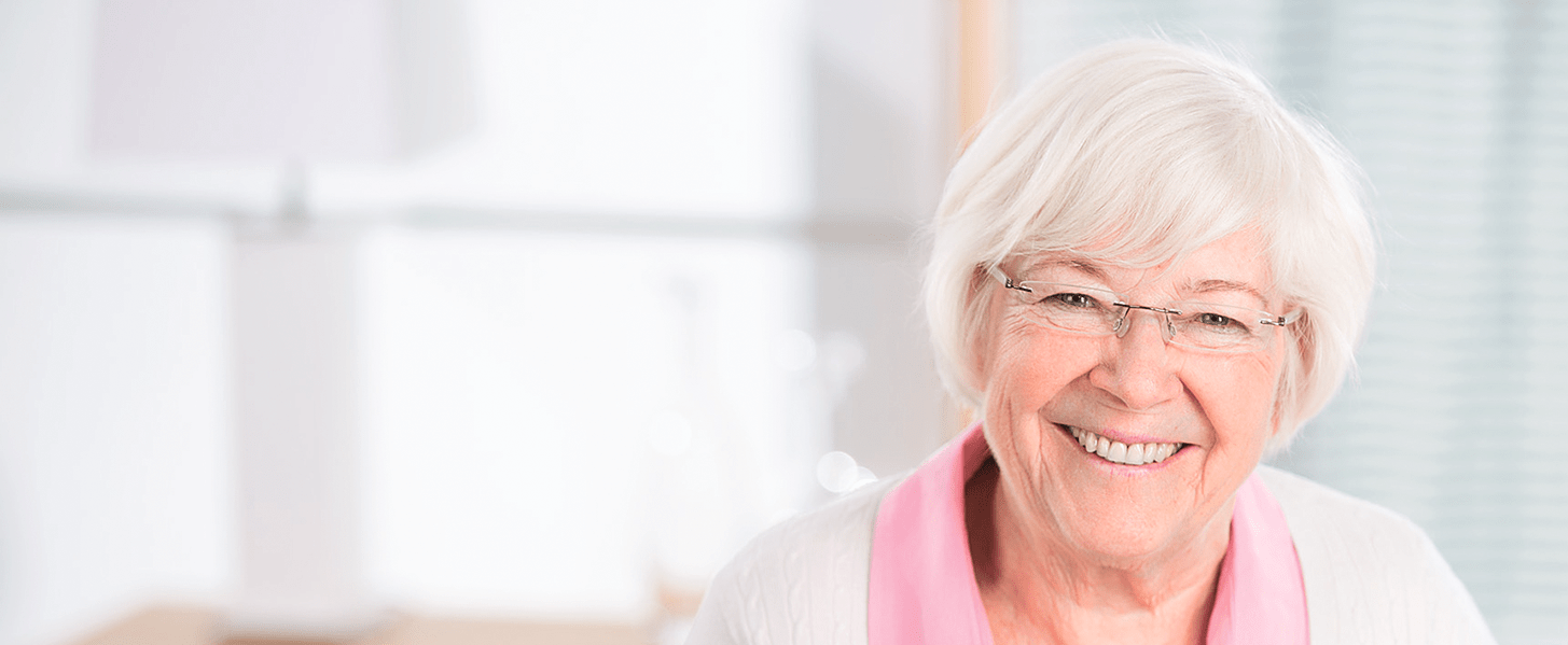 Porträt einer lächelnden älteren Frau mit Brille und weißem Haar