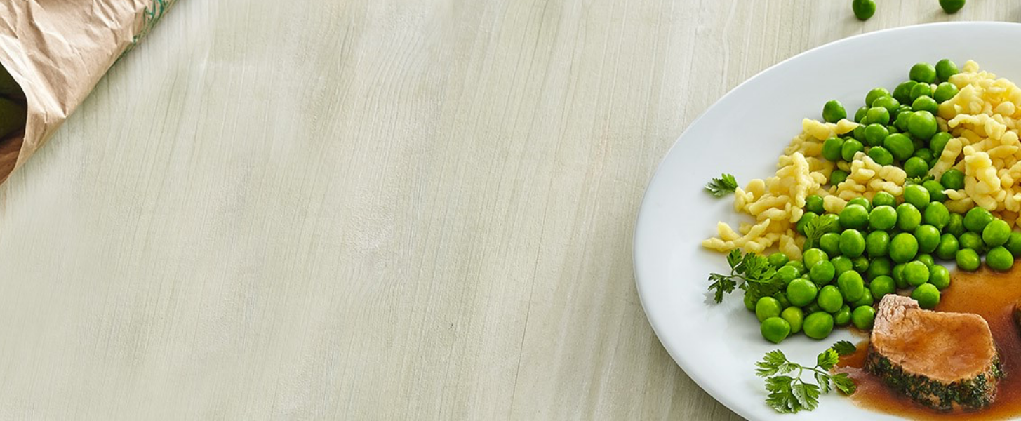 Teller mit Erbsen, Spätzle und Fleisch in brauner Soße