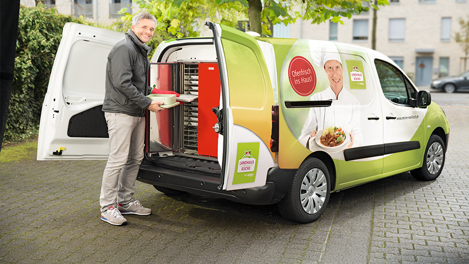 Eine Menükurier steht bei seinem Frischemobil